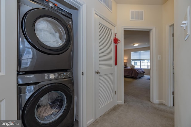 clothes washing area featuring estacked washer and dryer, light colored carpet, and baseboards