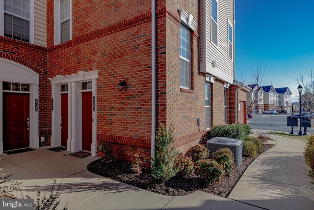 property entrance with central AC unit, a residential view, and brick siding