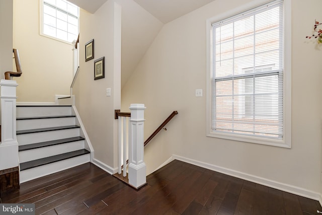staircase with wood-type flooring, baseboards, and vaulted ceiling