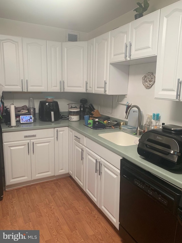 9039 Sligo Creek Pkwy Unit 706, Silver Spring, MD 20901 - kitchen with black dishwasher, a sink, white cabinets, light countertops, and light wood-style flooring