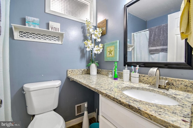 full bath with toilet, vanity, and baseboards