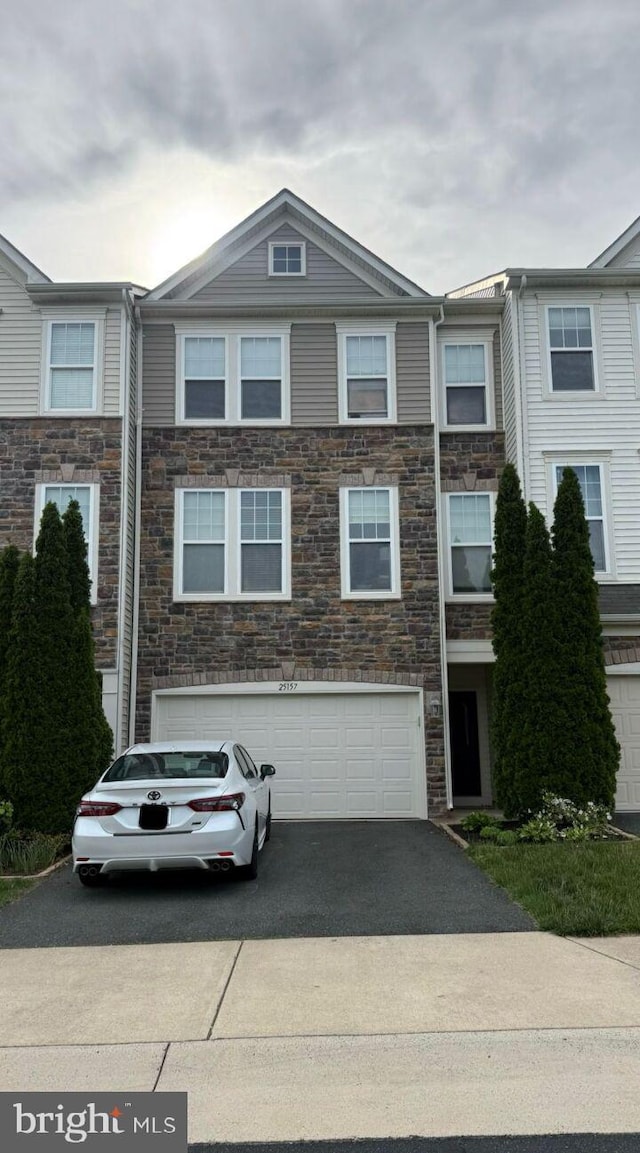 multi unit property featuring stone siding, asphalt driveway, and a garage