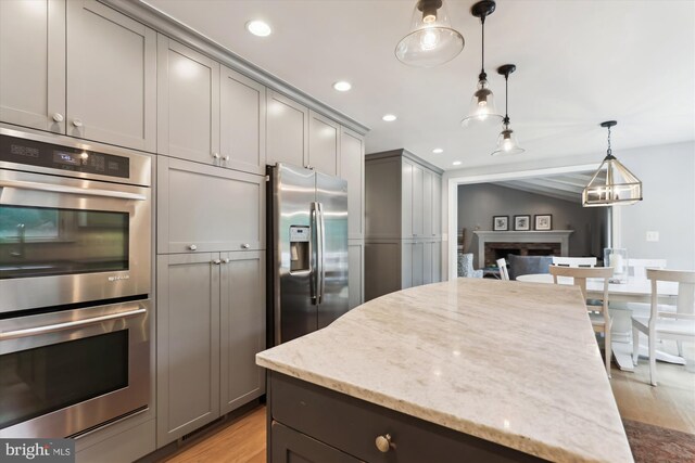 11476 Bronzedale Dr, Oakton, VA 22124 - kitchen featuring stainless steel appliances, gray cabinetry, light wood-style flooring, a fireplace, and light stone counters