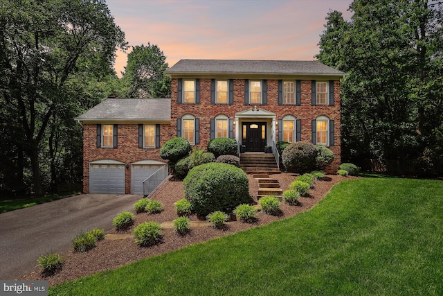 11476 Bronzedale Dr, Oakton, VA 22124 - colonial house featuring asphalt driveway, an attached garage, a yard, brick siding, and roof with shingles