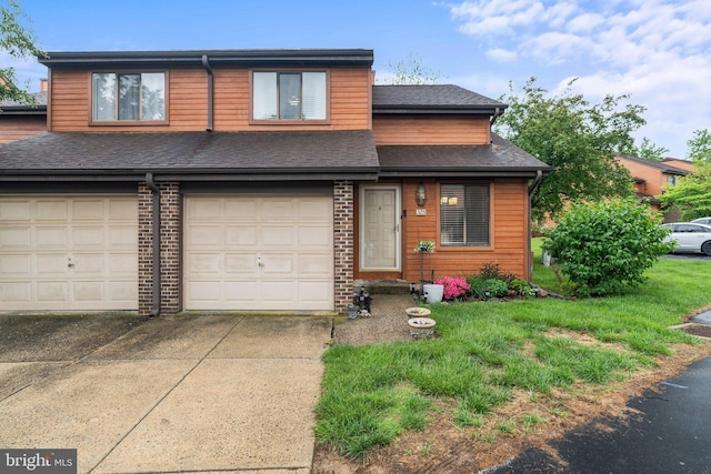 multi unit property with concrete driveway, a shingled roof, an attached garage, and a front yard