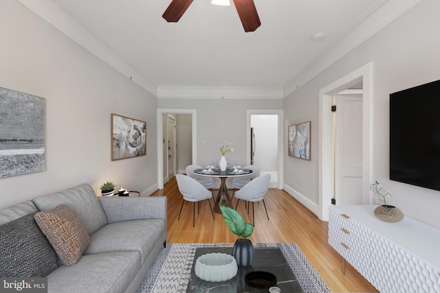 living area featuring ceiling fan, light wood-type flooring, ornamental molding, and baseboards