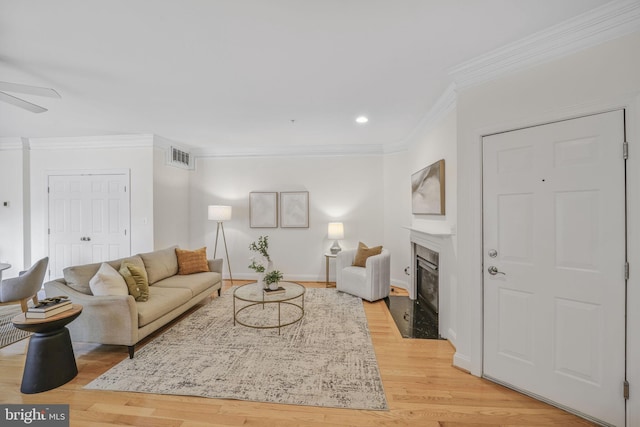 living area with crown molding, a fireplace with flush hearth, ceiling fan, light wood-style flooring, and recessed lighting