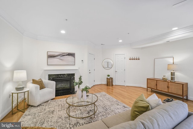 living room featuring ornamental molding, a fireplace, baseboards, recessed lighting, and wood finished floors
