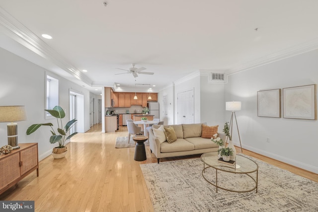 living area featuring crown molding, light wood-style floors, ceiling fan, baseboards, and recessed lighting