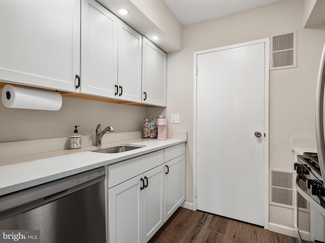 kitchen featuring dishwasher, a sink, white cabinets, dark wood-style flooring, and light countertops