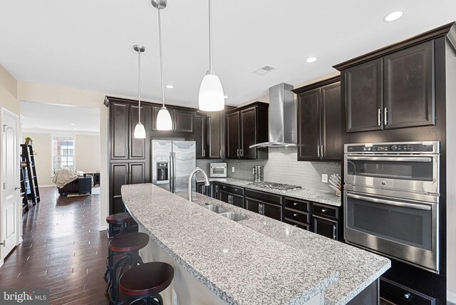 23483 Aldie Manor Ter, Ashburn, VA 20148 - kitchen featuring stainless steel appliances, wall chimney exhaust hood, a sink, recessed lighting, and a kitchen bar
