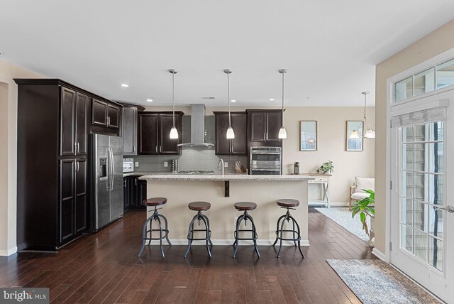 23483 Aldie Manor Ter, Ashburn, VA 20148 - kitchen featuring appliances with stainless steel finishes, wall chimney exhaust hood, dark brown cabinets, dark wood-style floors, and decorative backsplash