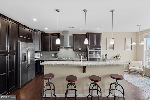 23483 Aldie Manor Ter, Ashburn, VA 20148 - kitchen with stainless steel appliances, wall chimney exhaust hood, dark wood-style flooring, decorative backsplash, and a kitchen bar