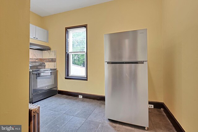 226 S 5th St, Reading, PA 19602 - kitchen featuring freestanding refrigerator, black electric range, under cabinet range hood, radiator, and baseboards