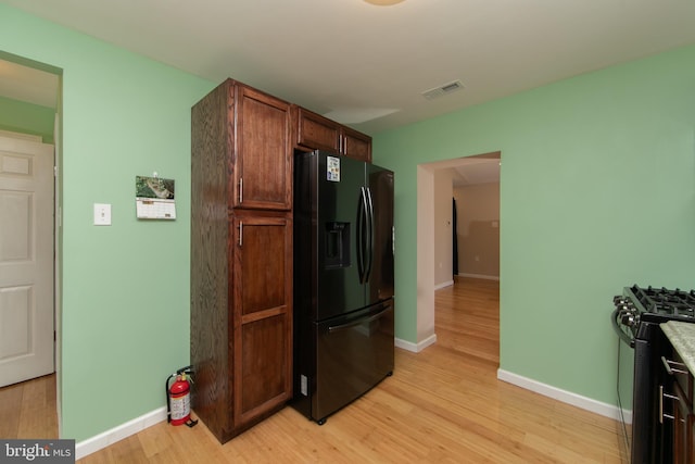 kitchen with black appliances, light wood-style flooring, and baseboards