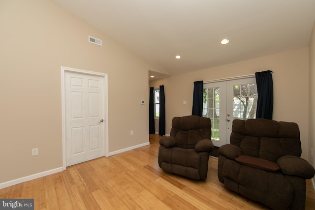living area featuring light wood finished floors, lofted ceiling, baseboards, recessed lighting, and french doors