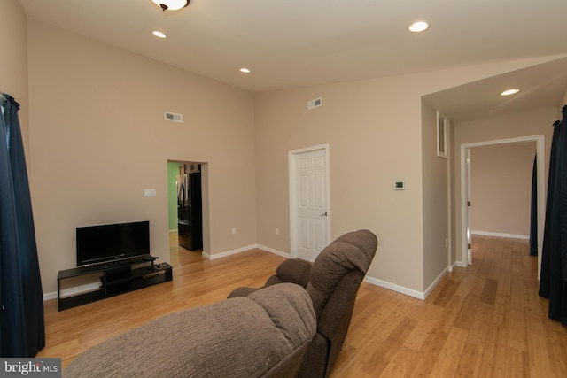 living room with light wood-style flooring, baseboards, recessed lighting, and a towering ceiling