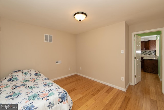 bedroom featuring light wood finished floors and baseboards