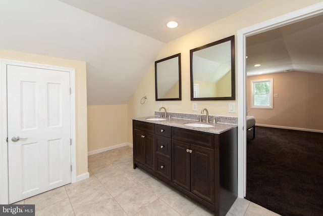 full bathroom with lofted ceiling, baseboards, double vanity, and tile patterned flooring
