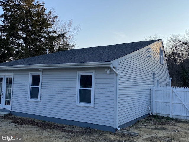 view of side of property featuring roof with shingles and french doors