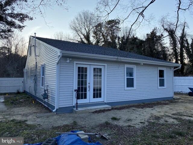 view of property exterior featuring french doors and a shingled roof
