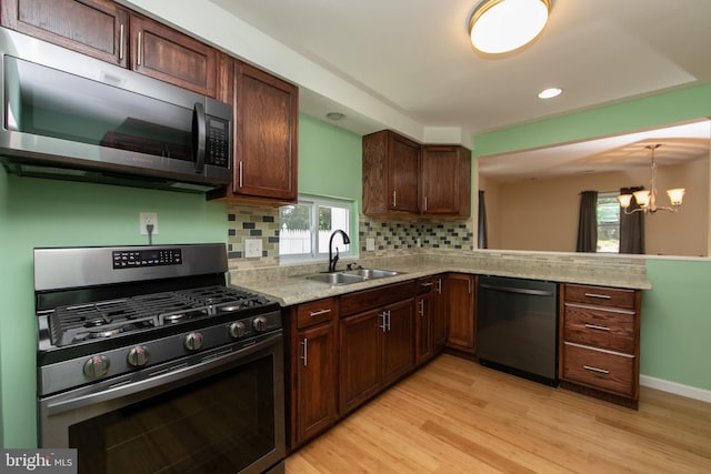kitchen with gas range, a sink, dishwasher, light wood finished floors, and tasteful backsplash