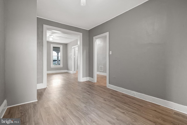 unfurnished room featuring a ceiling fan, wood finished floors, and baseboards