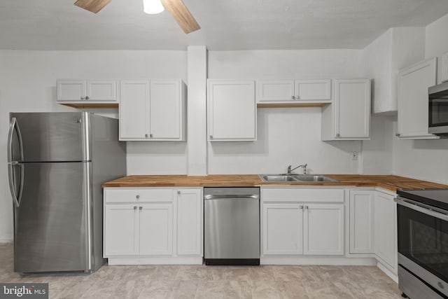 kitchen featuring appliances with stainless steel finishes, wood counters, a sink, and white cabinets