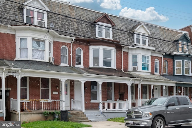 view of property featuring a porch and brick siding