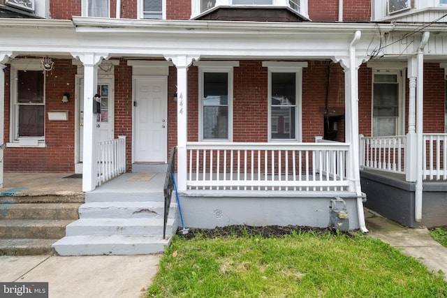 property entrance featuring a porch and brick siding