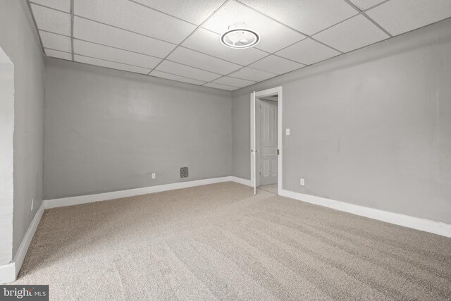 empty room featuring a drop ceiling, carpet floors, and baseboards