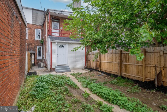 back of property with entry steps, a fenced backyard, a balcony, central air condition unit, and a chimney