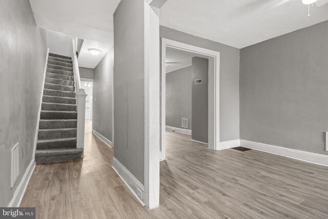 stairs with wood finished floors, baseboards, and a ceiling fan
