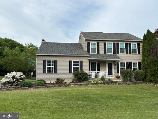 view of front of property with a porch, a front yard, and a chimney
