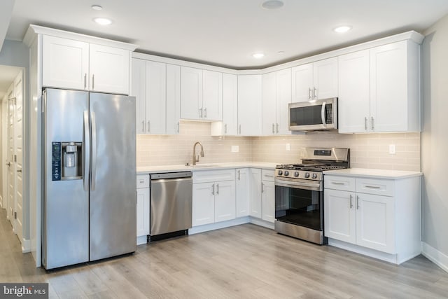 1309 S 52nd St, Philadelphia, PA 19143 - kitchen with stainless steel appliances, a sink, light countertops, light wood-style flooring, and white cabinets