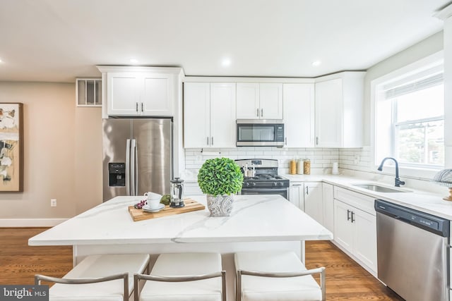 1778 Lang Pl NE, Washington, DC 20002 - kitchen featuring appliances with stainless steel finishes, a sink, backsplash, white cabinets, and light wood-type flooring