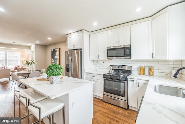 1778 Lang Pl NE, Washington, DC 20002 - kitchen with appliances with stainless steel finishes, a sink, a breakfast bar, light wood-style floors, and white cabinetry