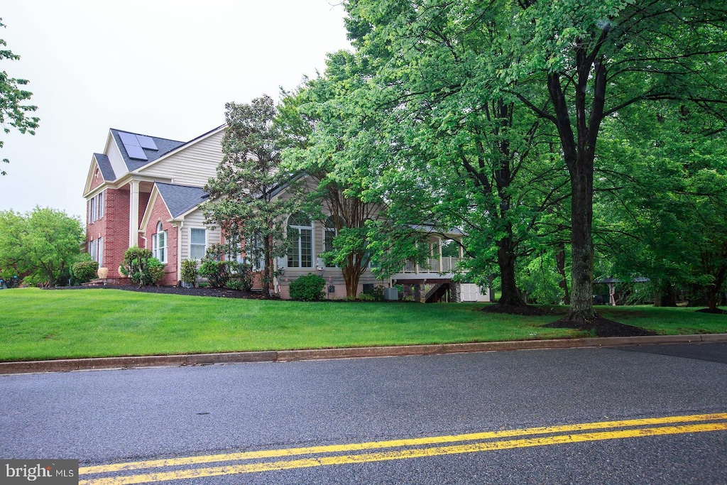 obstructed view of property featuring a front yard, brick siding, and solar panels