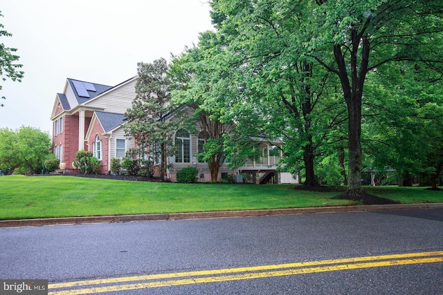 obstructed view of property featuring a front yard, brick siding, and solar panels
