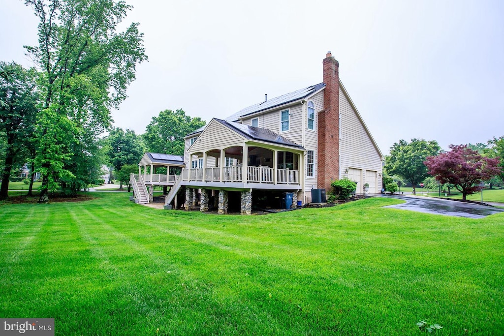 back of property featuring a garage, a yard, a chimney, and asphalt driveway