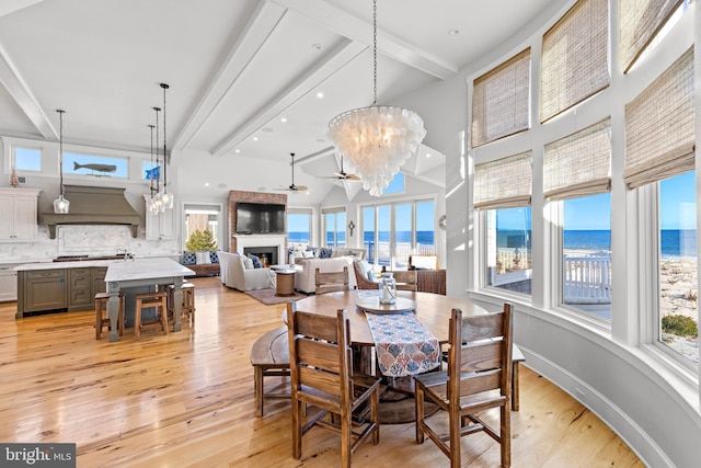 6601 Ocean Blvd, Long Beach Township, NJ 08008 - dining space featuring a chandelier, beam ceiling, a fireplace, light wood-style floors, and plenty of natural light