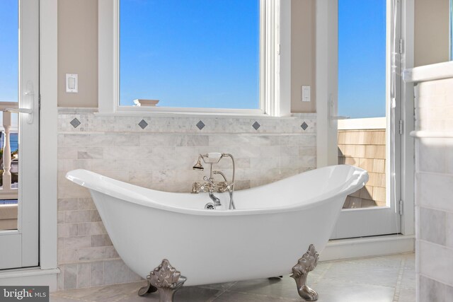 6601 Ocean Blvd, Long Beach Township, NJ 08008 - bathroom with tile walls, a freestanding tub, wainscoting, and tile patterned flooring