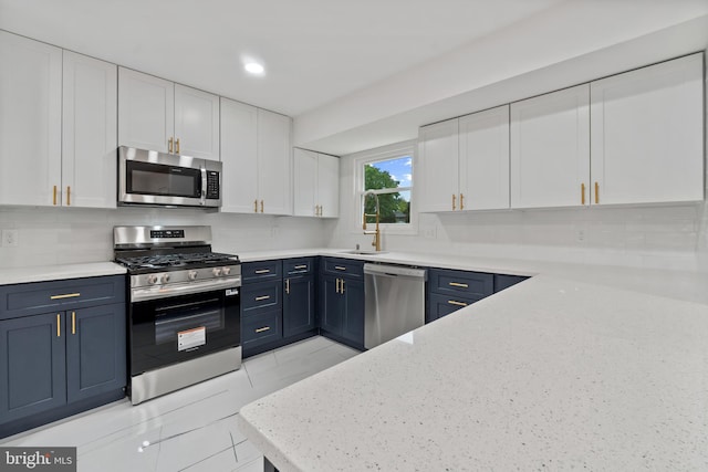 kitchen with stainless steel appliances, blue cabinets, white cabinets, and tasteful backsplash