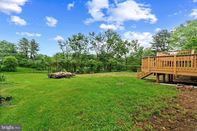 view of green lawn featuring a deck and stairs