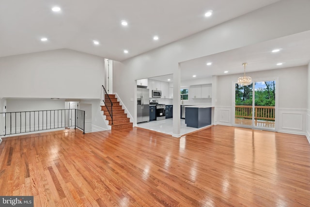 unfurnished living room with a chandelier, a decorative wall, light wood-style floors, recessed lighting, and wainscoting
