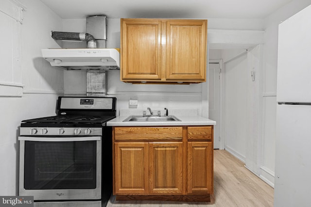 2943 Gransback St, Philadelphia, PA 19134 - kitchen featuring stainless steel gas range, a sink, freestanding refrigerator, under cabinet range hood, and light wood-style floors