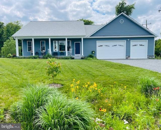 view of front of property featuring gravel driveway, covered porch, a garage, and a front yard