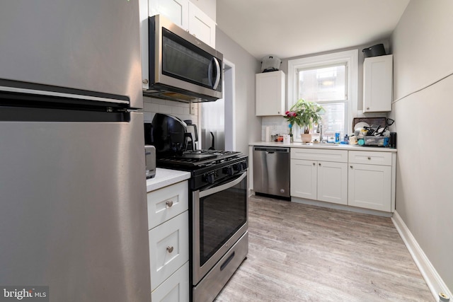 4504 Vista St, Philadelphia, PA 19136 - kitchen featuring stainless steel appliances, decorative backsplash, light countertops, white cabinets, and light wood-type flooring