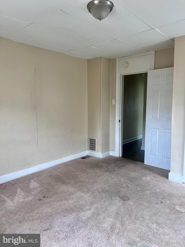 empty room with carpet floors, baseboards, and a paneled ceiling