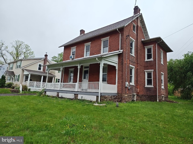 view of front facade with a chimney, covered porch, brick siding, and a front lawn